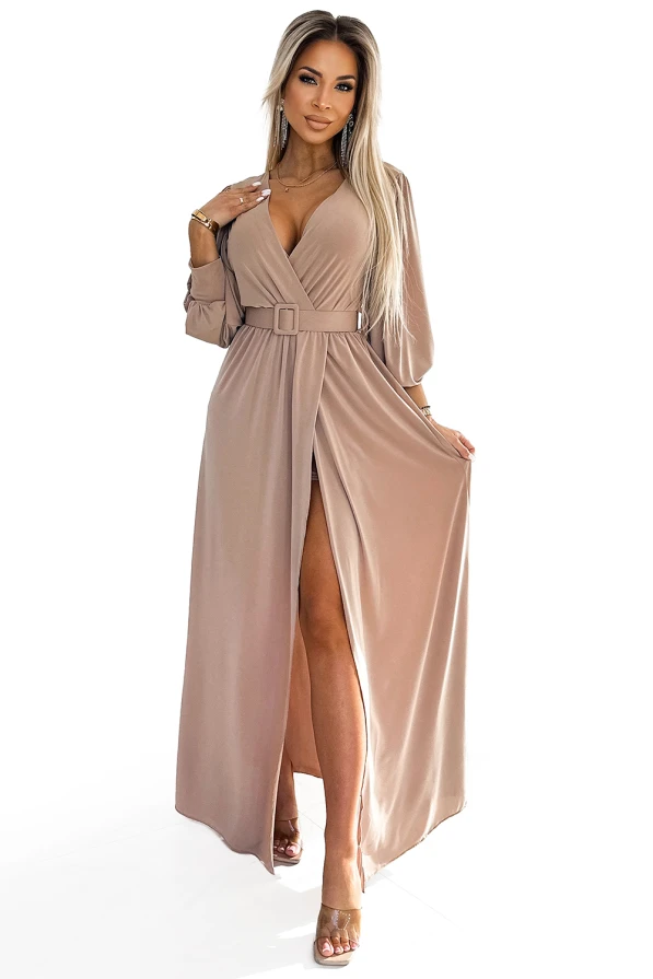Dlouhé šaty Fiorella v elegantní béžové barvě mají hluboký výstřih a stylový pásek v pase. Splývavý materiál a rozparek dodávají šatům sofistikovaný vzhled.