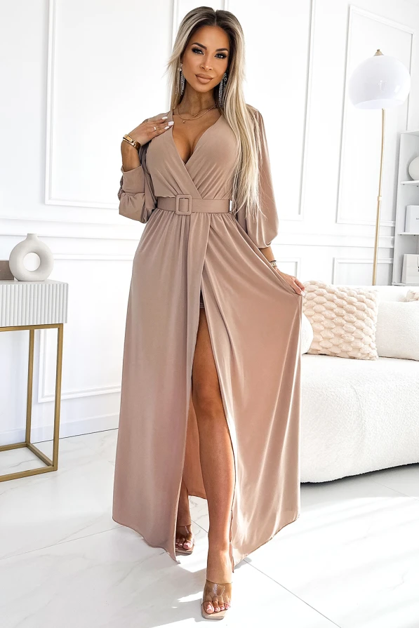 Dlouhé šaty v elegantní béžové barvě s hlubokým výstřihem a páskem v pase. Šaty mají rozparek, který dodává sofistikovaný a moderní vzhled.
