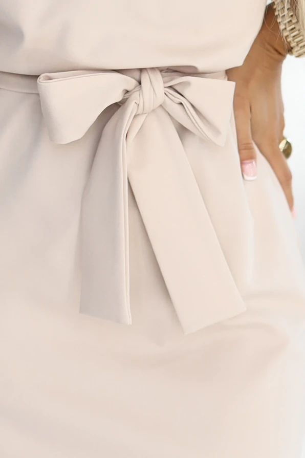 Beżowa elegancka sukienka marki Numoco, z krótkim rękawem, dekoltem typu woda i wiązaniem w talii, uszyta z elastycznego, wysokiej jakości materiału. Produkt polski, idealny na pracę, przyjęcia i wyjątkowe okazje.