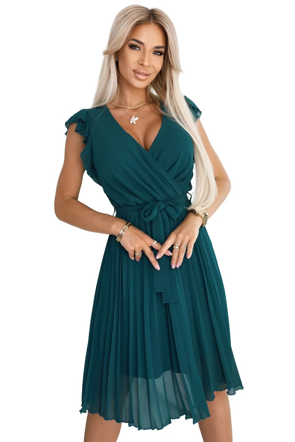 Modelka w zielonej plisowanej sukience z kopertowym dekoltem i wiązaniem w talii – elegancka propozycja od polskiej marki Numoco na wesele, przyjęcia, randkę lub rodzinne uroczystości. Produkt polski.