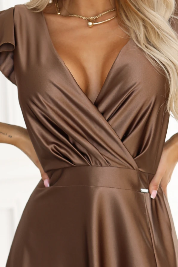Modelka z gracją prezentuje błyszczącą suknię wieczorową Numoco z satyny w odcieniu Mocha Mousse, ukazując jej lekkość i eleganckie wykończenie.