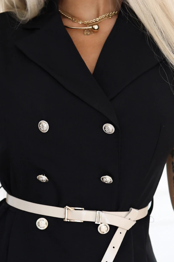Modelka prezentuje czarną elegancką sukienkę midi bez rękawów z ozdobnymi guzikami i beżowym paskiem w talii od Numoco Basic, stojąc w jasnym, nowoczesnym wnętrzu. Stylowa, klasyczna propozycja idealna na lato, spotkania i codzienne stylizacje.