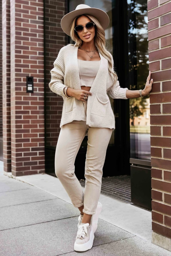 Modelka prezentuje beżową narzutkę z dzianiny marki Numoco Basic, idealną na chłodniejsze dni.